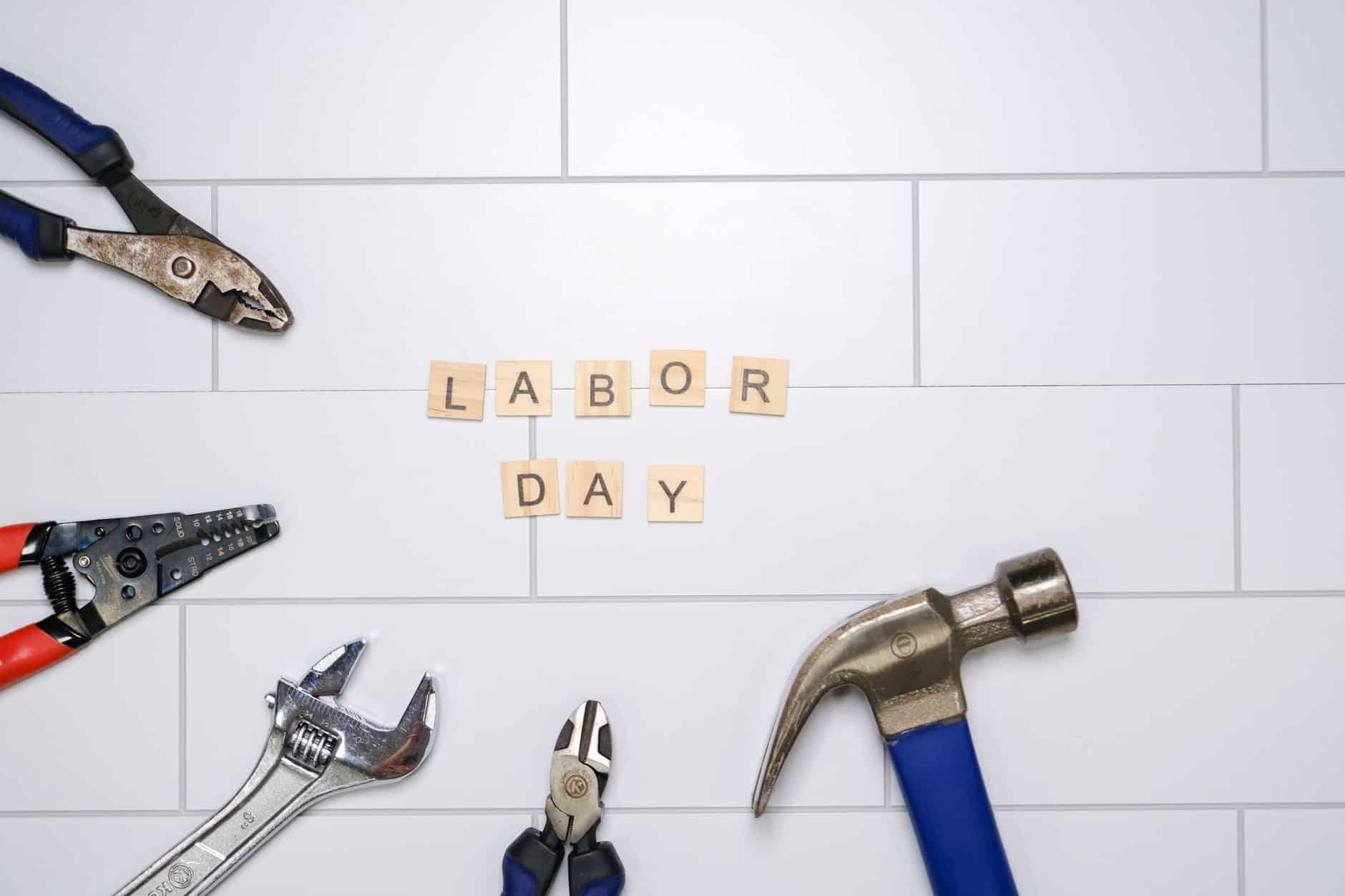 Small business website advice Plumber day rate: flat lay of various tools and 'Labor Day' letters on white tiles. Perfect for Labor Day themes